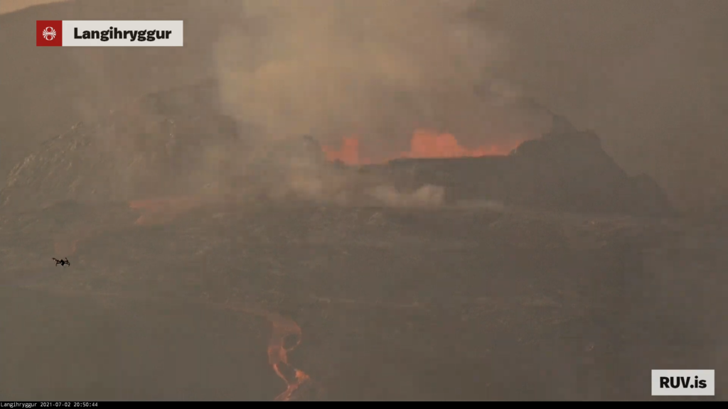 Red hot lava from the crater flows down on Rúv web camera. Small drown is in frame of the shot.