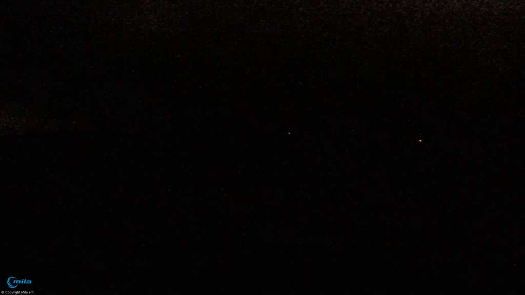 Black image showing two light dots. With the dot on the left being a car or some human made noise. While the dot on the right might be a small eruption that is unconfirmed.