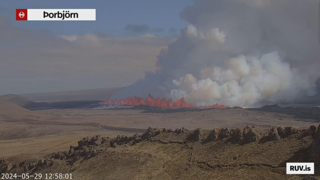 The eruption fissure seen from Þorbjörn mountain today at 12:58:01. A large gas cloud is coming from the eruption in a day that is slight cloudy but with sun at that moment.